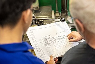Auszubildender und Ausbilder schauen einen Plan an