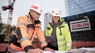 Photo of ZÜBLIN colleagues discussing something whilst looking at a construction plan