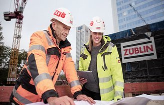 Foto von ZÜBLIN-Kolleg:innen, die gerade etwas anhand eines Bauplans besprechen