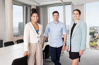 Foto von einem Mann in einem Schulungsraum, im Hintergrund arbeiten vier Mitarbeiter