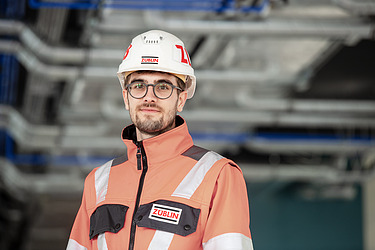 A young man on a building site wearing high-visibility clothing