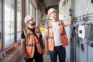 Photo of two ZÜBLIN colleagues standing on a building site
