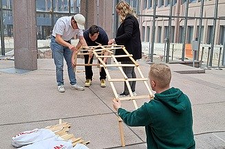 Vier junge Personen bauen eine Leonardobrücke