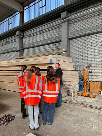 Kinder in Arbeitsschutzkleidung stehen in der Produktionshalle von ZÜBLIN Timber.