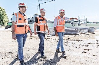 Foto von drei Männern, die eine Baustelle besichtigen 