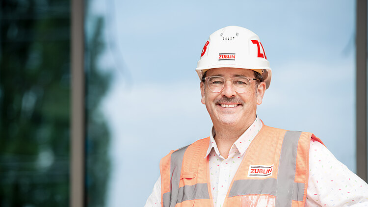 A ZÜBLIN employee wearing a hard hat and a high-visibility vest.
