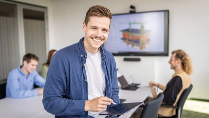 Drei Mitarbeitende lächeln in einem Besprechungsraum.