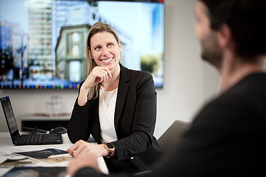 Foto von einer Projektleiterin, die in einem Meetingraum sitzt.