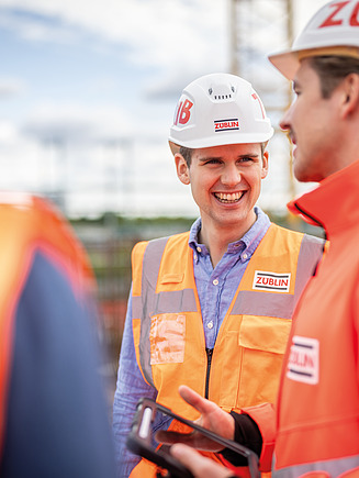 Drei Mitarbeiter auf der Baustelle in einer Besprechungssituation