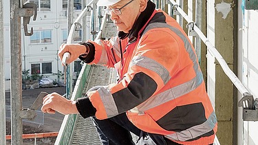 Foto von einem Mann auf der Baustelle, der das Gerüst befestigt 